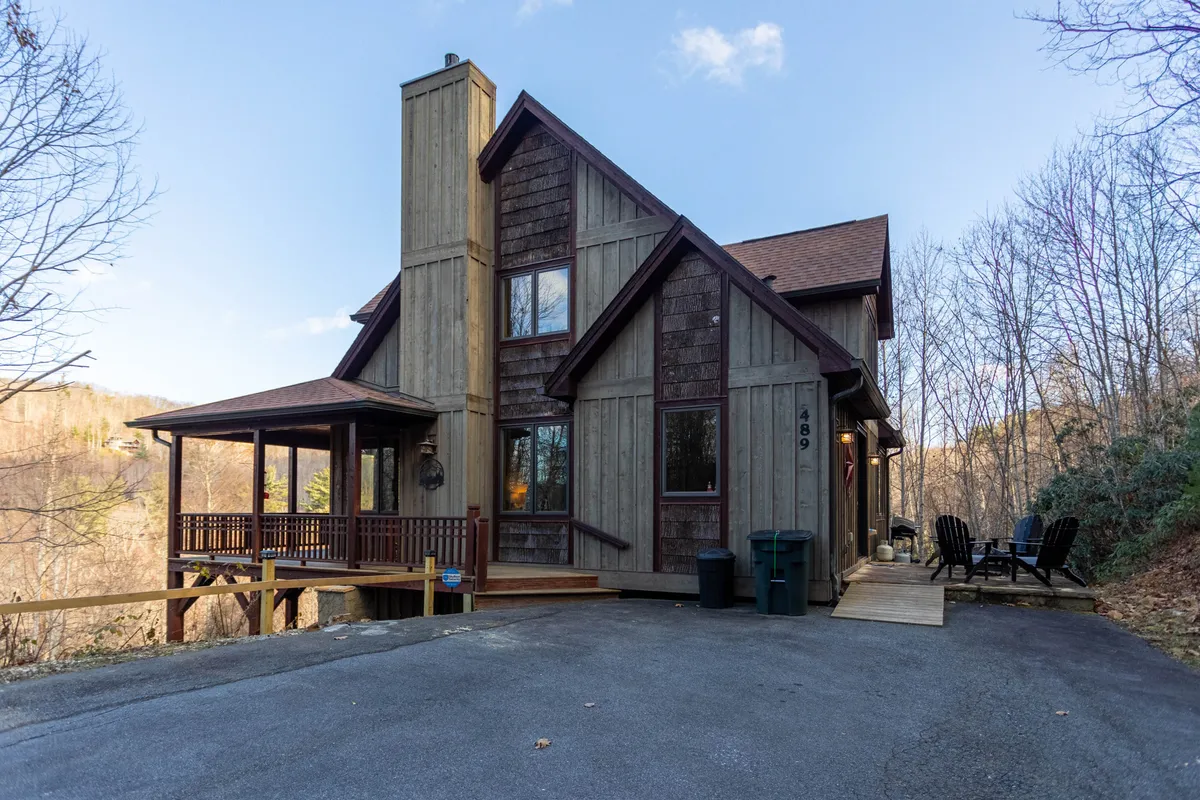 This image captures the front porch of Headwaters Hideaway, featuring an asymmetrical roofline, wooden siding, large windows, and inviting porch seating. Surrounded by nature, the home exudes privacy and luxury from the very first impression, setting the tone for an upscale mountain retreat.