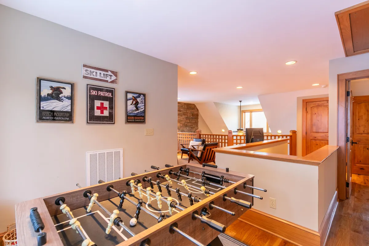 A lively loft scene with a foosball table, ski-themed artwork, and wooden railing, evoking a sense of fun and social gathering. The decor and setting suggest a dedicated play and unwind area ideal for kids, teens, and adults alike.